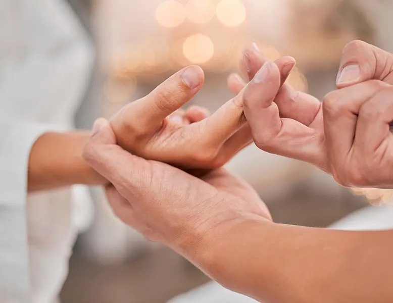 Physiotherapist supporting an older patient's wrist during an arthritis assessment
