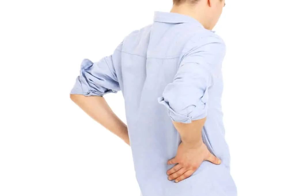 Person holding their lower back, illustrating the typical pain pattern of lumbar strain